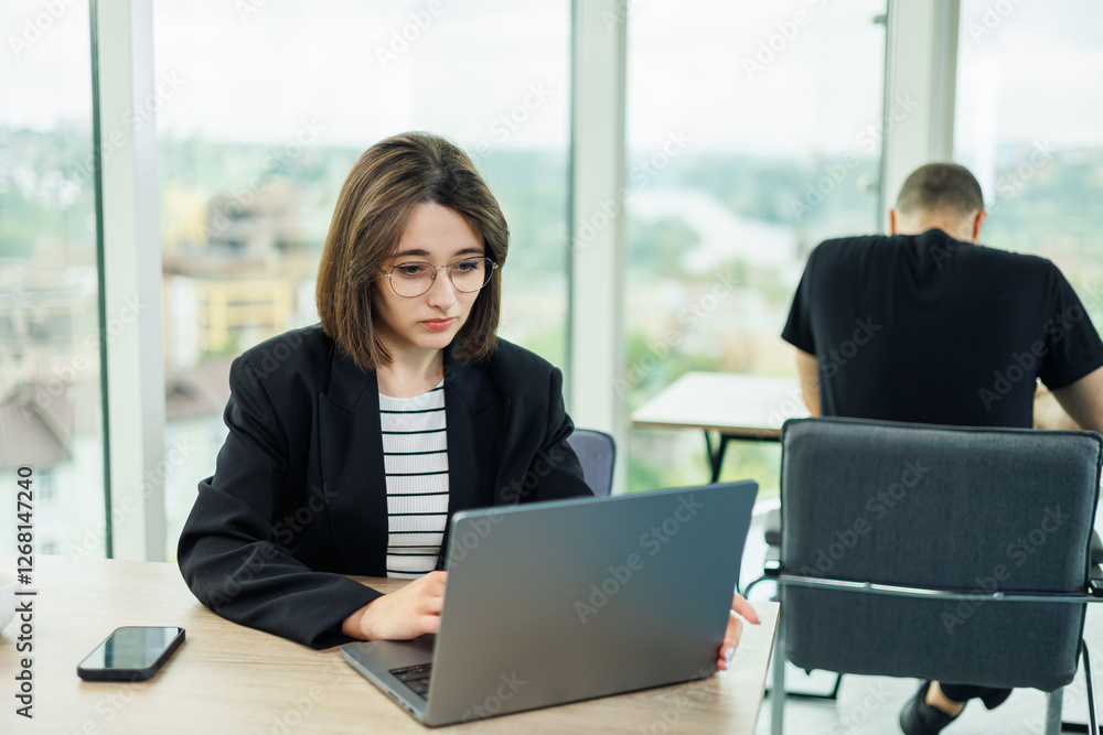 Smiling business woman, company employee, working holding laptop while sitting in modern office. Modern business woman working online. Smiling business woman, company employee, working holding laptop while sitting in modern office. Modern business woman working online.