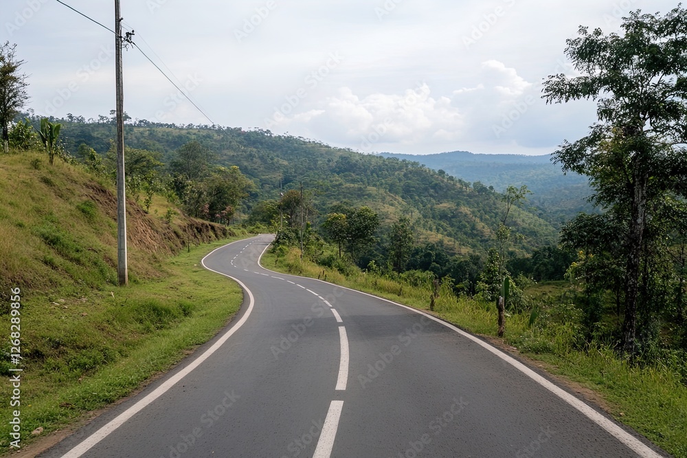 Winding country road through lush green hills on a cloudy day in rural landscape