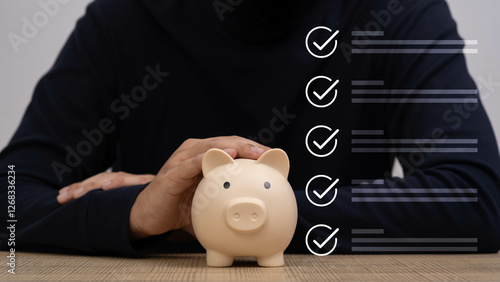 A close-up of a person holding a piggy bank, representing budgeting and savings with a checklist in the background, emphasizing financial planning.