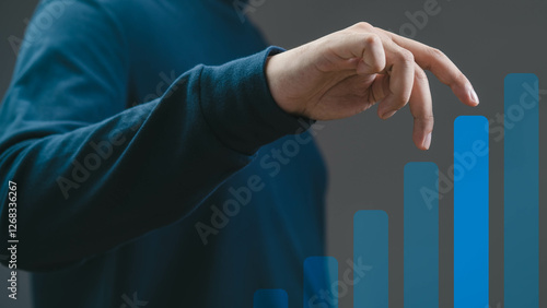 A close-up of a hand pointing at an upward growth graph, symbolizing progress and success in a professional business environment.