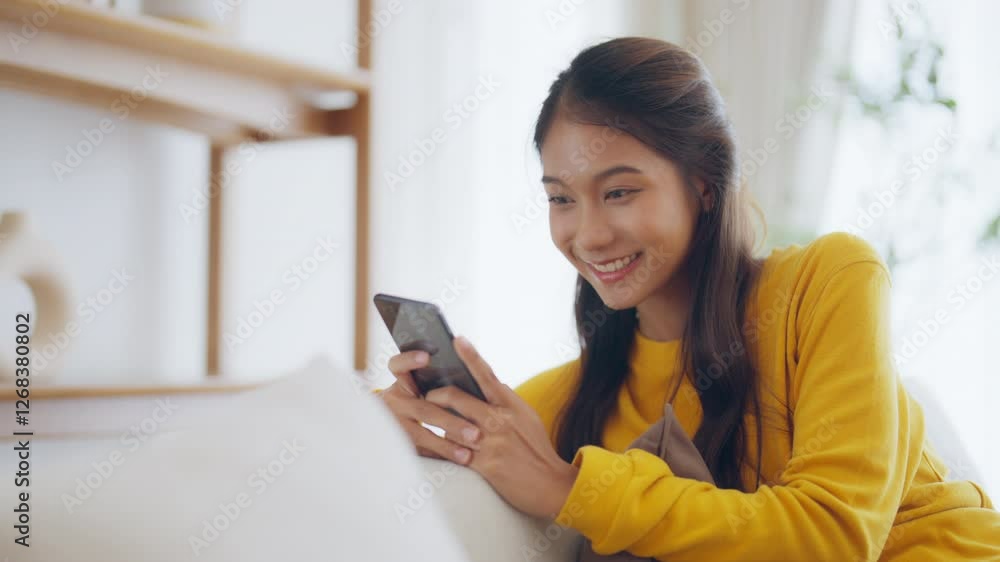 Happy young asian woman relax on comfortable couch at home texting messaging on smartphone, smiling girl use cellphone chatting, online shopping at home, video call communication Happy young asian woman relax on comfortable couch at home texting messaging on smartphone, smiling girl use cellphone chatting, online shopping at home, video call communication