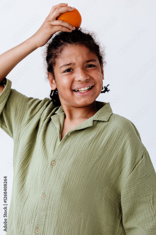 Cute young boy posing with fresh orange fruit against plain white background Cute young boy posing with fresh orange fruit against plain white background