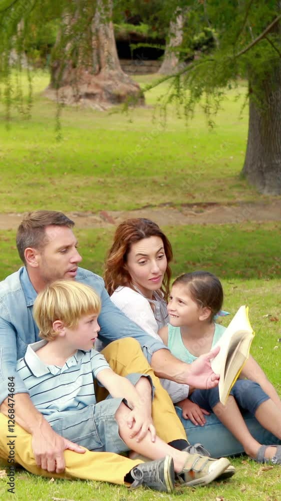 Happy family sitting on grass and reading book Happy family sitting on grass and reading book