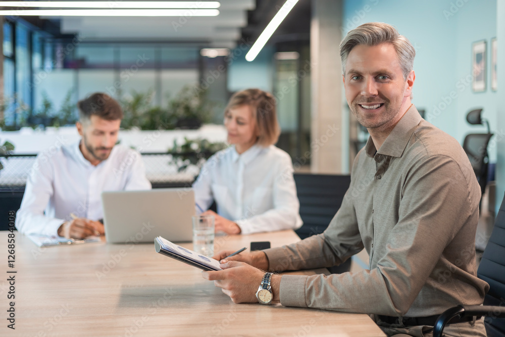 Businessman with his staff, people group in background at modern bright office indoors. Businessman with his staff, people group in background at modern bright office indoors.