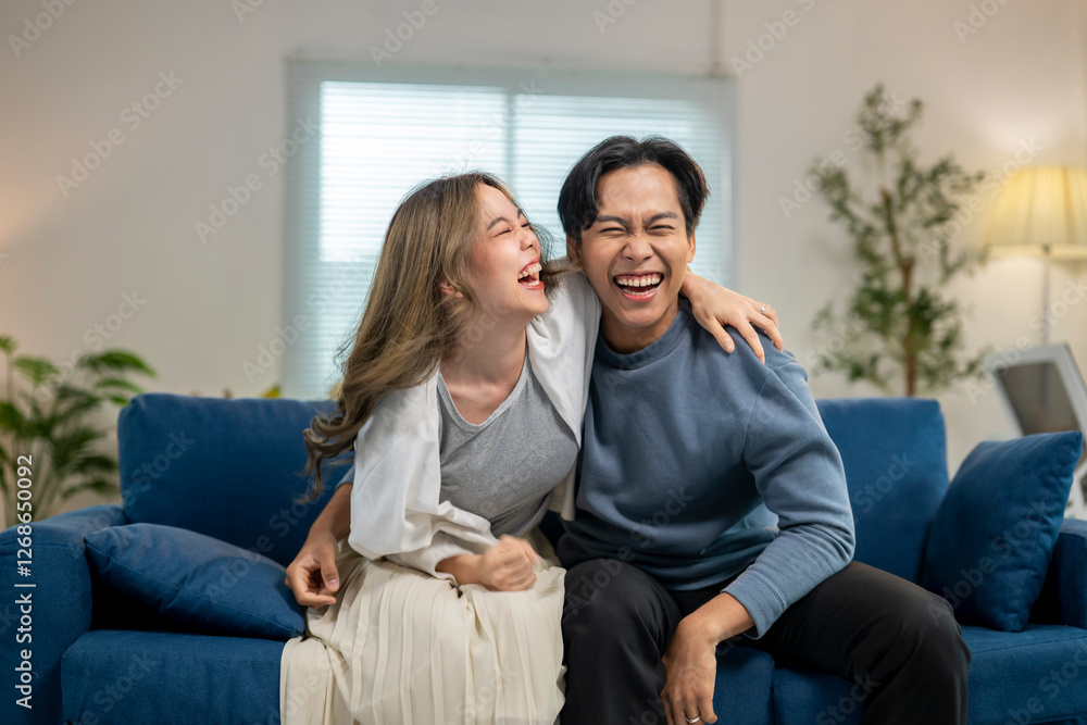 Obraz premium A man and a woman are sitting on a blue couch, laughing and hugging each other