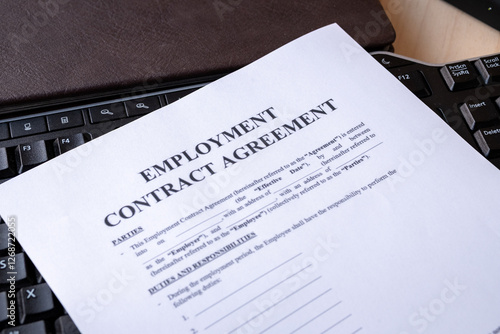 Employment Contract on Black Keyboard with Notepad and Pen on Wooden Background