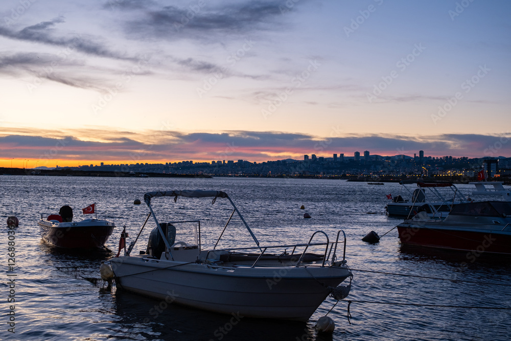 Fototapeta premium Boats silhouetted sunrise sky background. Peaceful sunrise scene with fishing boats anchored in the harbor on calm sea. Golden horizon, early morning at bay