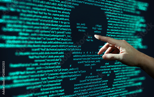 Human hand points at abstract Modern tech of Programming code screen with skull. Computer Virus, Malware, and Hacker Attack Concept.