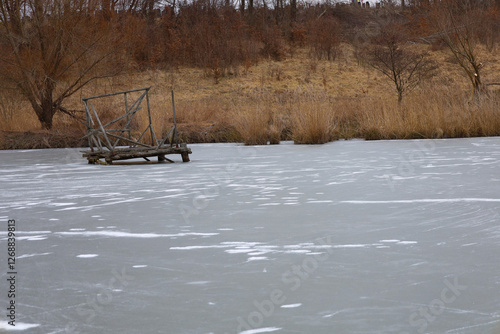 Fényképezés Old wooden platform in the middle of an ice-bound pond
