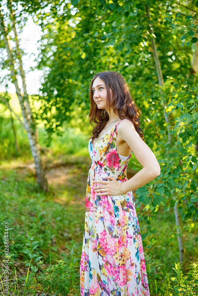 A beautiful girl in a bright dress walks in the park in summer in sunny weather. A beautiful girl in a bright dress walks in the park in summer in sunny weather.