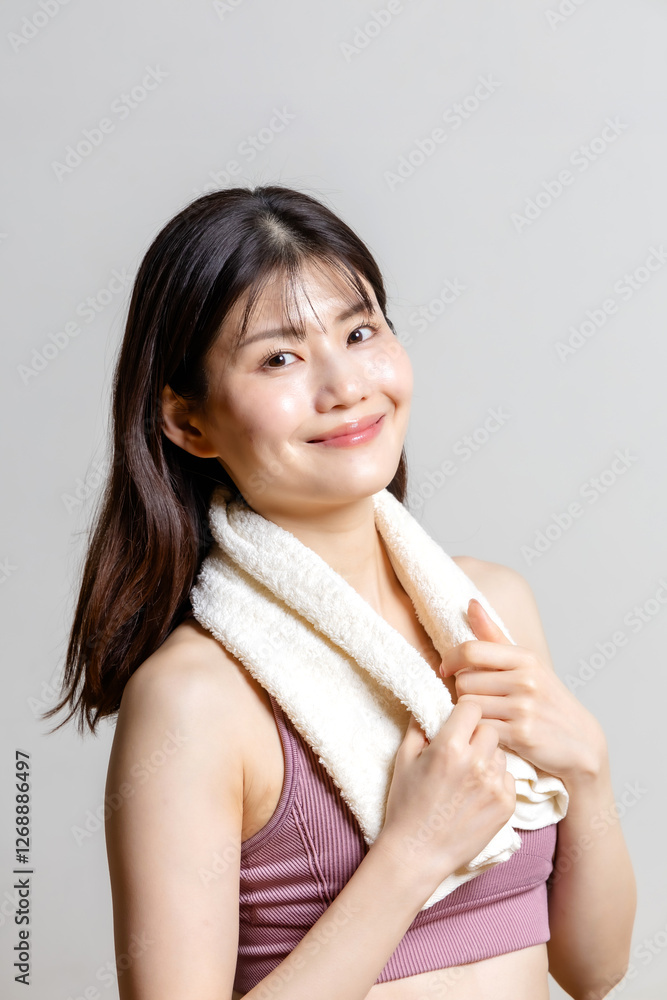 タオルを首にかけてポーズをとるスポーツウェアの美しい女性