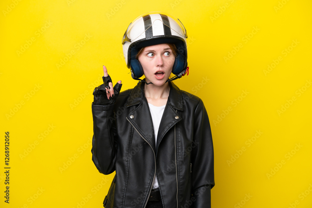 Young English woman with a motorcycle helmet isolated on yellow background thinking an idea pointing the finger up Young English woman with a motorcycle helmet isolated on yellow background thinking an idea pointing the finger up