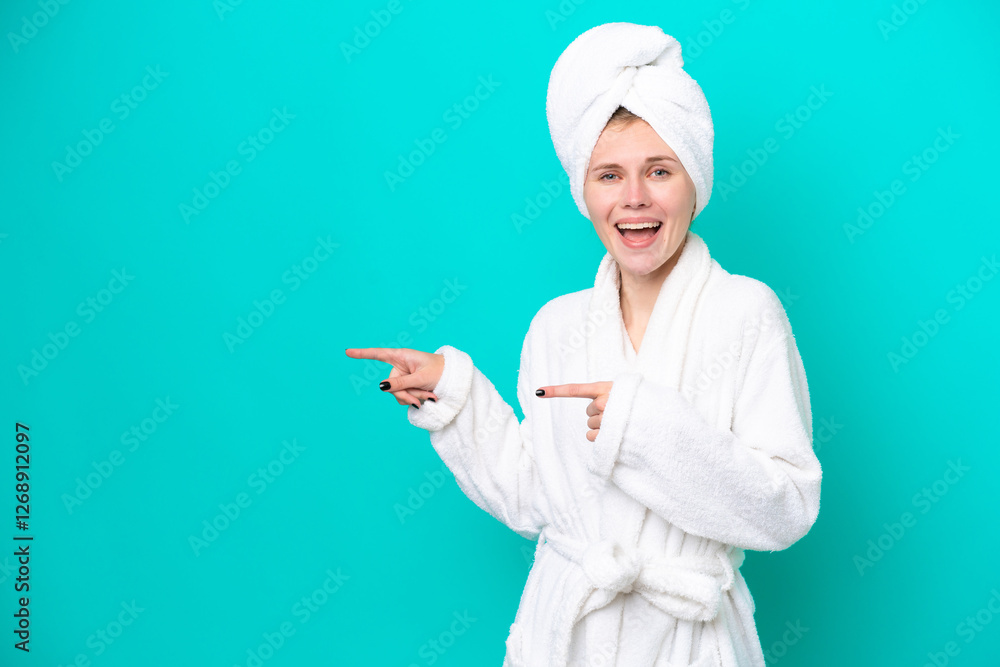 Young woman in a bathrobe isolated on blue background surprised and pointing side Young woman in a bathrobe isolated on blue background surprised and pointing side