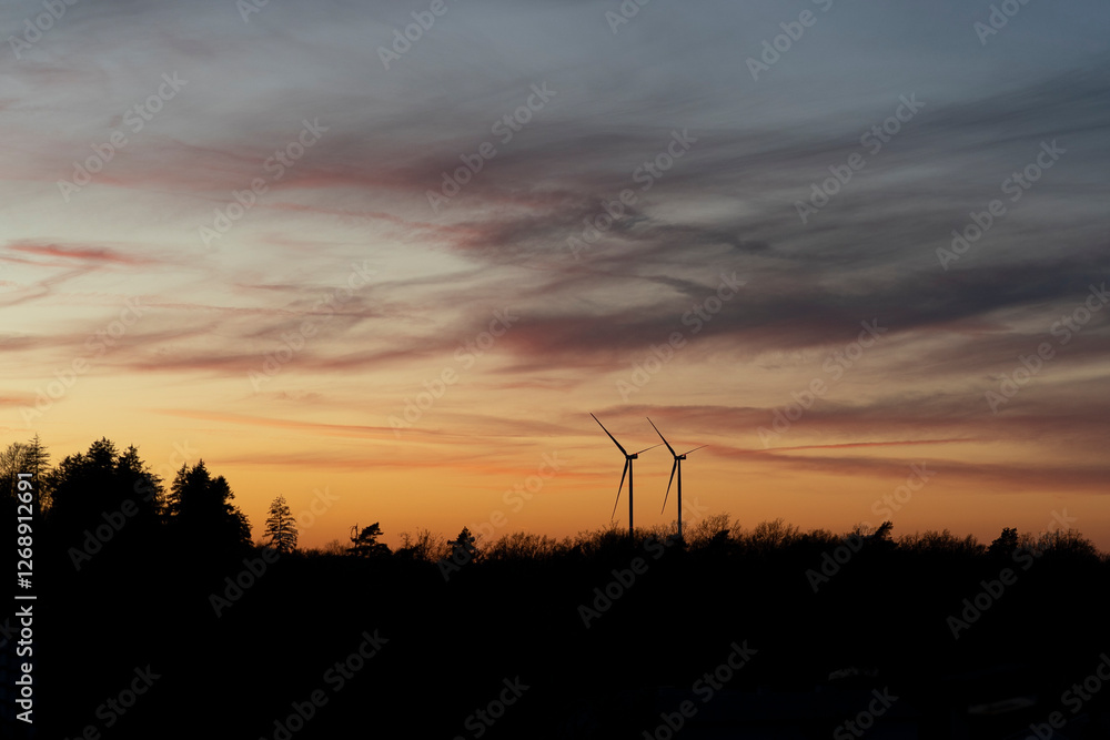 Two wind turbines against an orange-blue sunset in Germany. Renewable energy concept Two wind turbines against an orange-blue sunset in Germany. Renewable energy concept