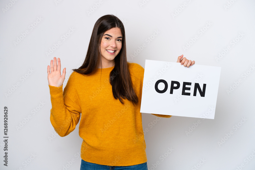 Young Brazilian woman isolated on white background holding a placard with text OPEN and saluting Young Brazilian woman isolated on white background holding a placard with text OPEN and saluting