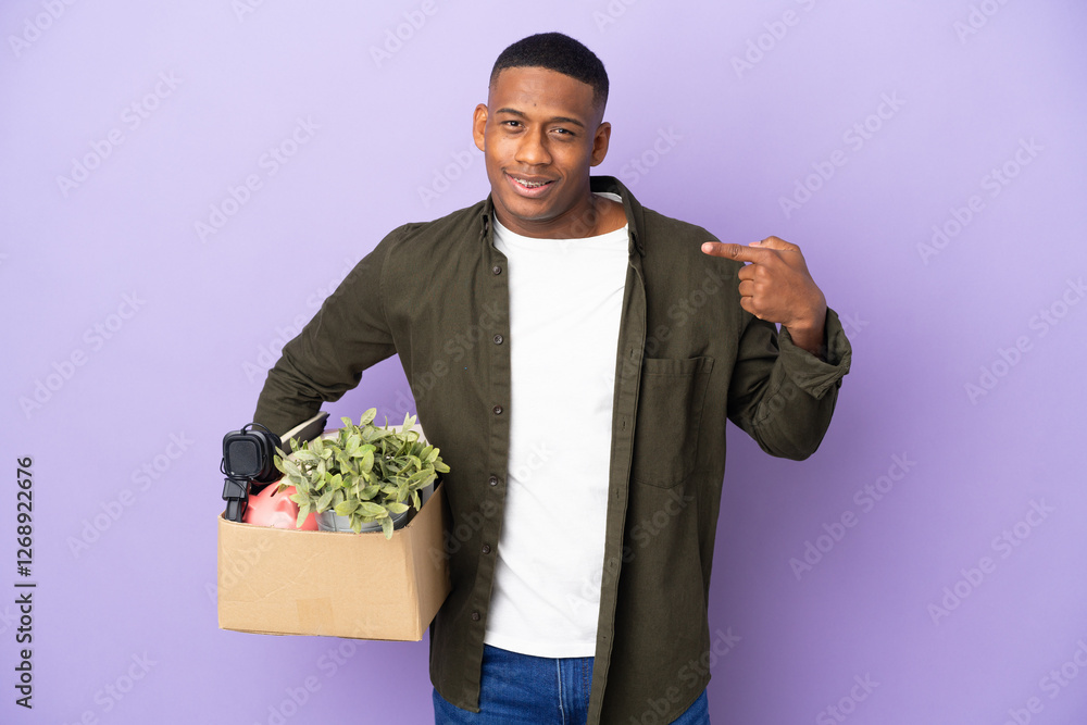 Latin man making a move while picking up a box full of things giving a thumbs up gesture Latin man making a move while picking up a box full of things giving a thumbs up gesture
