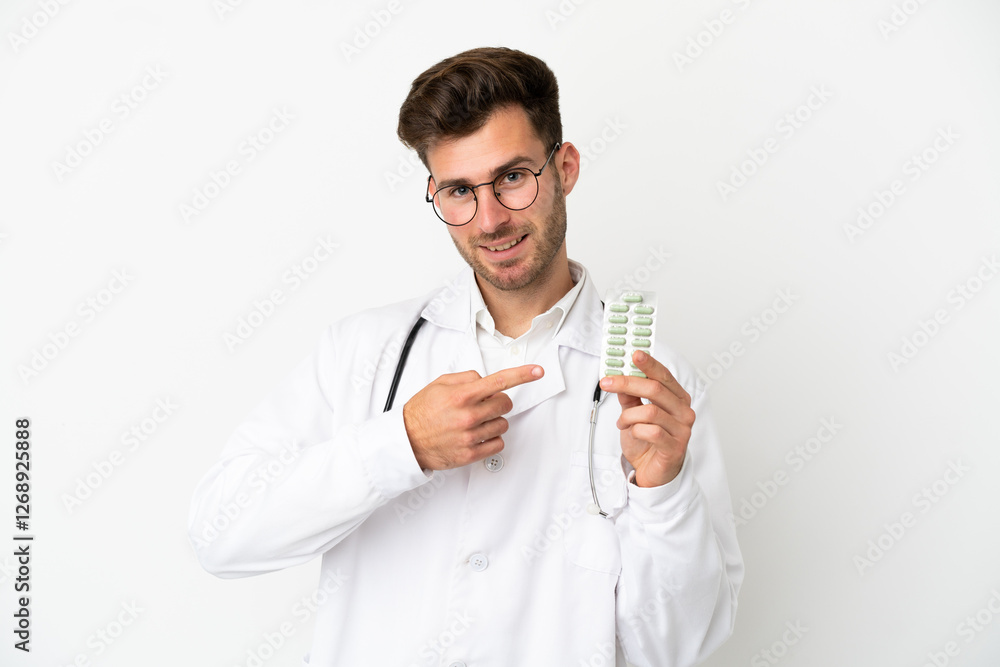 Young doctor caucasian man over isolated on white background wearing a doctor gown and holding pills Young doctor caucasian man over isolated on white background wearing a doctor gown and holding pills
