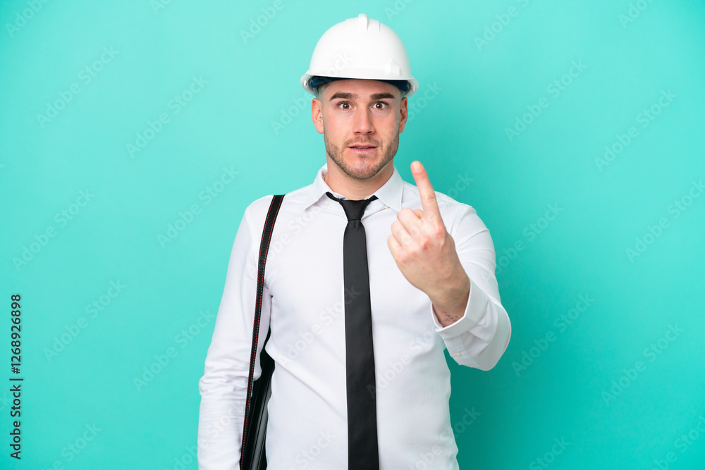 Young architect caucasian man with helmet and holding blueprints isolated on blue background doing coming gesture Young architect caucasian man with helmet and holding blueprints isolated on blue background doing coming gesture