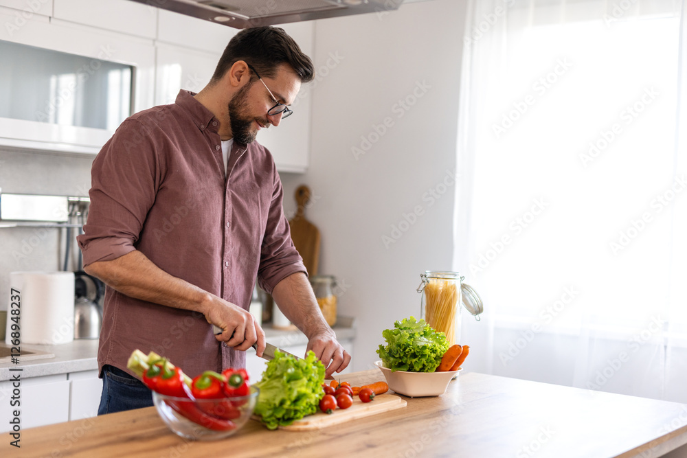 Handsome young man man stand at modern kitchen chop vegetables prepare fresh vegetable salad for dinner or lunch, young male cooking at home make breakfast follow healthy diet, vegetarian concept Handsome young man man stand at modern kitchen chop vegetables prepare fresh vegetable salad for dinner or lunch, young male cooking at home make breakfast follow healthy diet, vegetarian concept