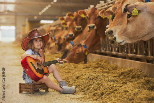 Charming child in a cowboy costume sings for cows on a farm in Denmark