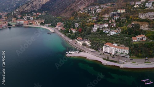aerial view of sailboats moored in harbor with crystal clear water and built coast nearby in lake garda