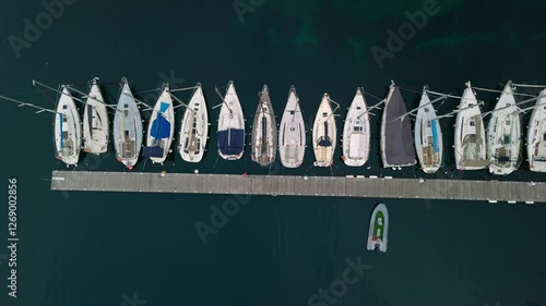 aerial view of sailboats moored in harbor with crystal clear water and built coast nearby in lake garda
