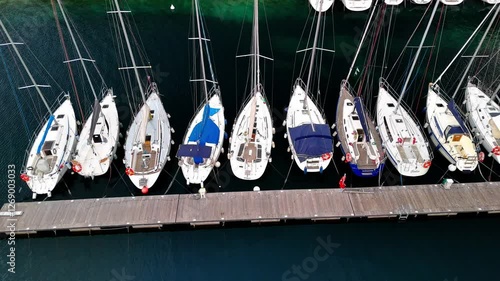 aerial view of sailboats moored in harbor with crystal clear water and built coast nearby in lake garda