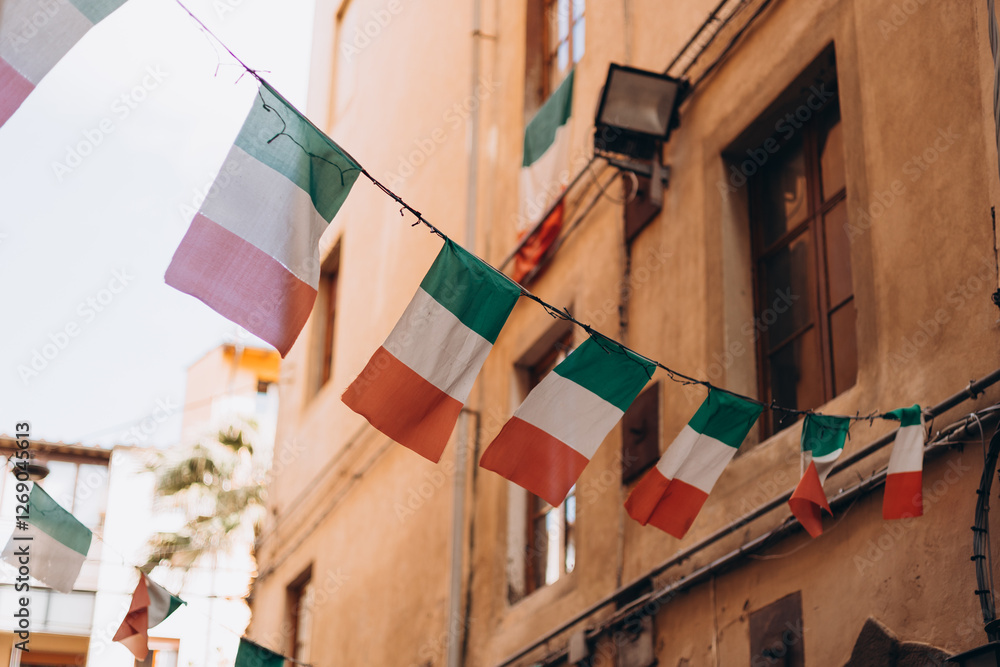 Typical street with houses in Italy. Facade of a yellow building with Italian flags. Italian flag in an old town narrow street of a city in Italy