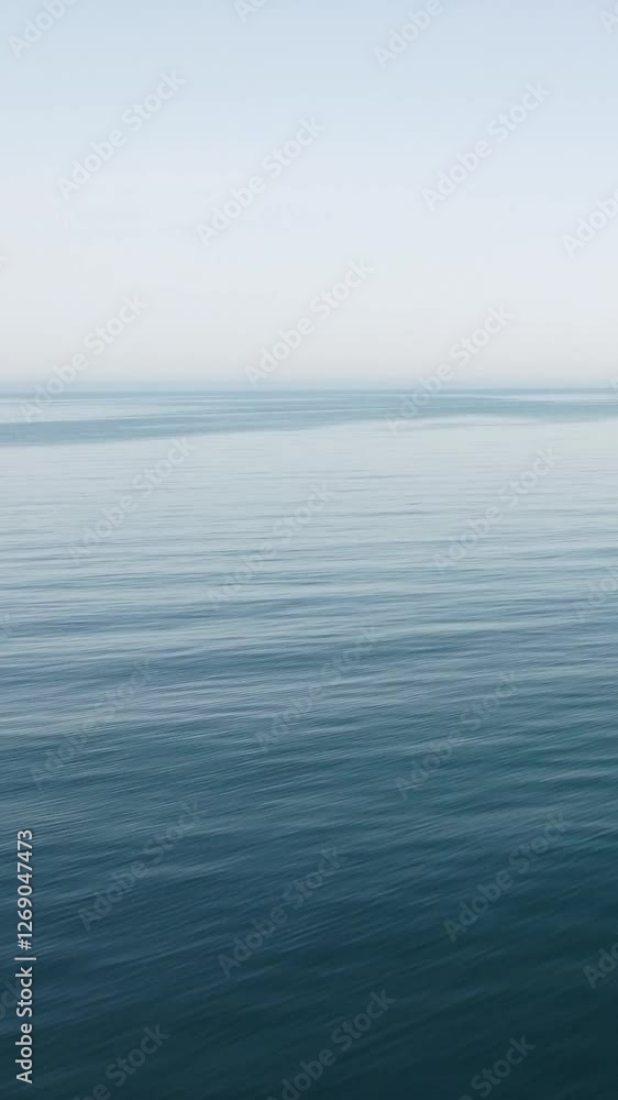 Vertical aerial view over calm sea water surface. Sun glare. Abstract nautical summer ocean nature. Holiday, vacation and travel concept. Nobody. Weather and climate change Vertical aerial view over calm sea water surface. Sun glare. Abstract nautical summer ocean nature. Holiday, vacation and travel concept. Nobody. Weather and climate change