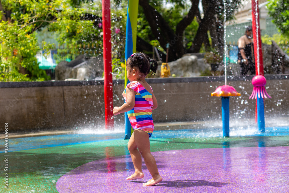 Adorable little girl enjoy play in colorful city child water park outdoor activity