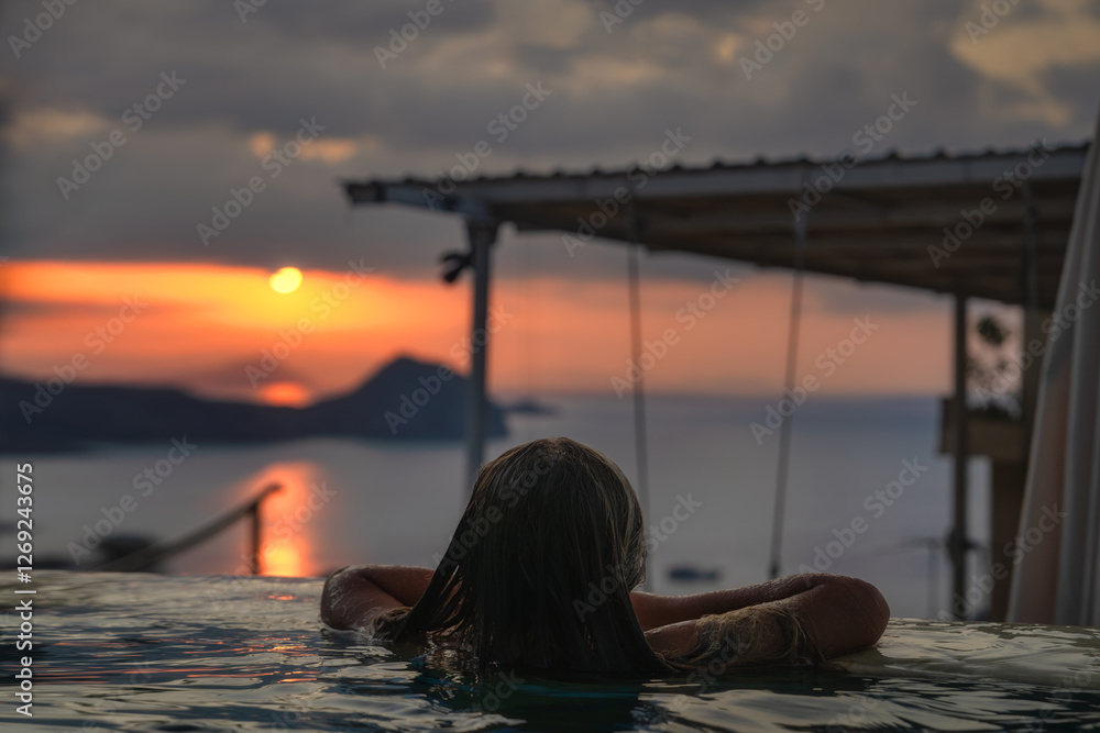 In a serene and tranquil setting, a person finds joy as they take in the breathtaking view of a sunset unfolding over the vast ocean from an infinity pool, Komodo, Indonesia
