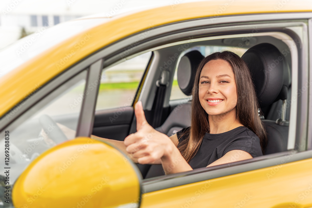 A young woman with long brown hair and a bright smile sits in the driver's seat of a yellow car, giving a thumbs-up gesture through the open window with a confident and positive expression.
