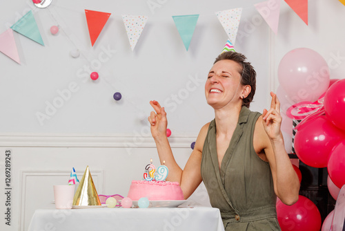 Crossed fingers woman laughing make a wish at birthday party photo