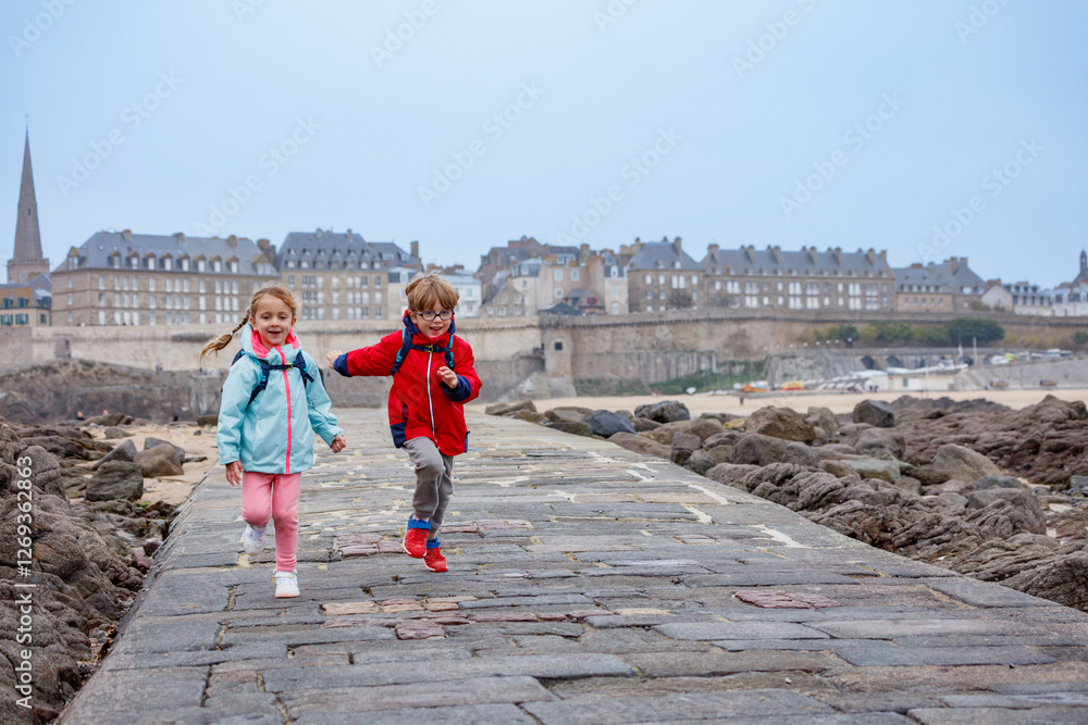 Children enjoying joyful run on a seaside walkway in Saint-Malo