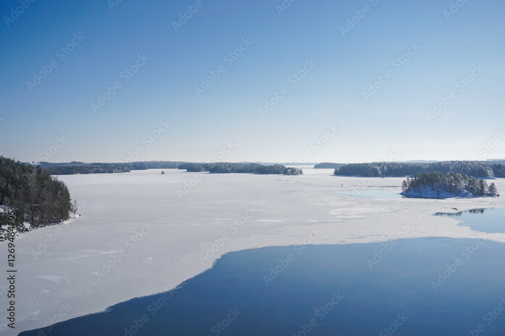Beautiful winter lake landscape. View on the high bridge. Frozen lake, islands, forest and blue sky. Winter season in Finland. Beautiful winter lake landscape. View on the high bridge. Frozen lake, islands, forest and blue sky. Winter season in Finland.