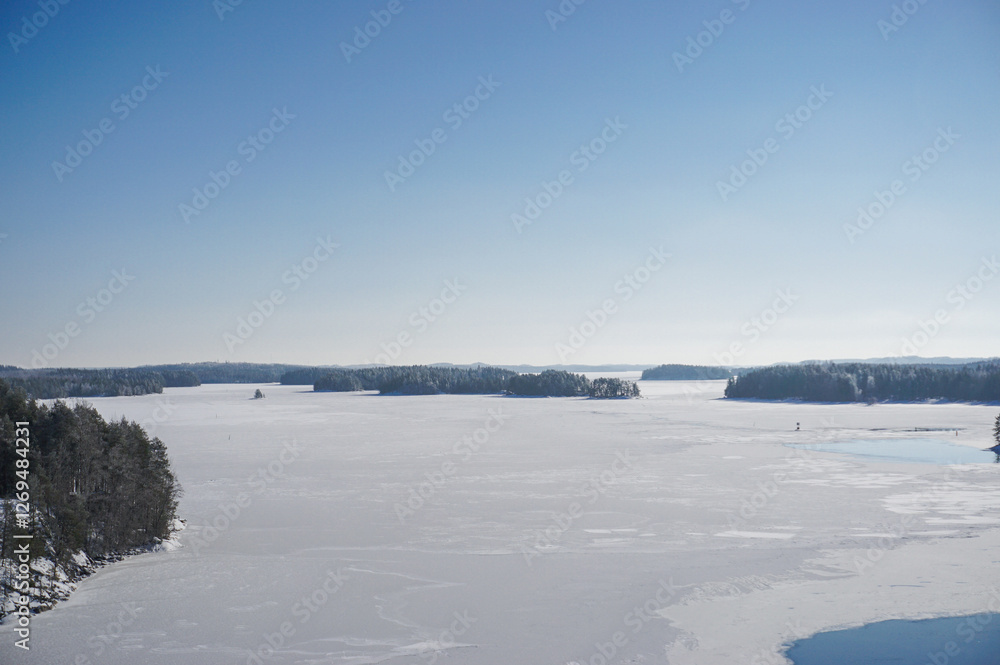 Beautiful winter lake landscape. View on the high bridge. Frozen lake, islands, forest and blue sky. Winter season in Finland. Beautiful winter lake landscape. View on the high bridge. Frozen lake, islands, forest and blue sky. Winter season in Finland.