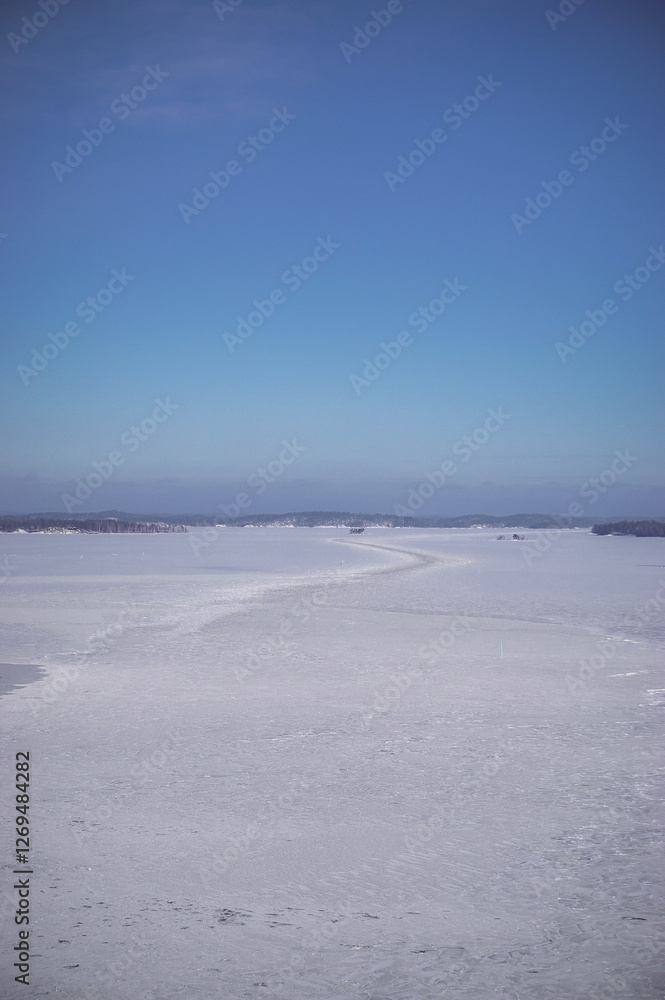 Beautiful winter lake landscape. View on the high bridge. Frozen lake, islands, forest and blue sky. Winter season in Finland. Beautiful winter lake landscape. View on the high bridge. Frozen lake, islands, forest and blue sky. Winter season in Finland.