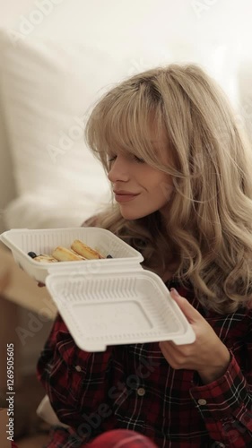 Charming young blonde girl enjoying food in bed. Food delivery. Vertical frame