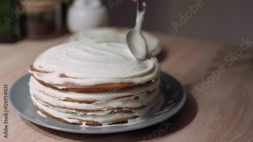 Sweet cream being applied and spread over the sponge cake layer, cake decoration and assembling