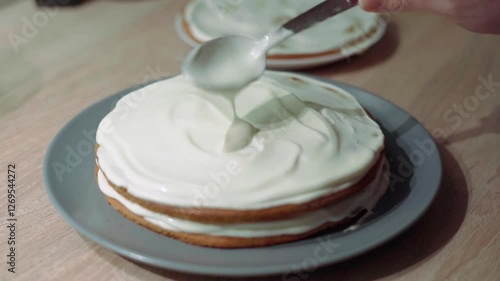 Sweet cream being applied and spread over the sponge cake layer, cake decoration and assembling