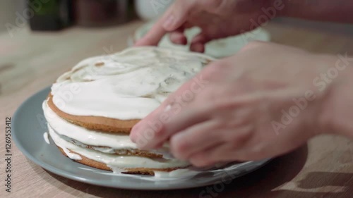 woman assembling a cake from layers of sponge biscuit