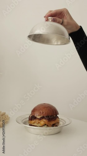Burger under a metal lid. Serving, delicacy, Mockup for serving and delivering food. Vertical frame