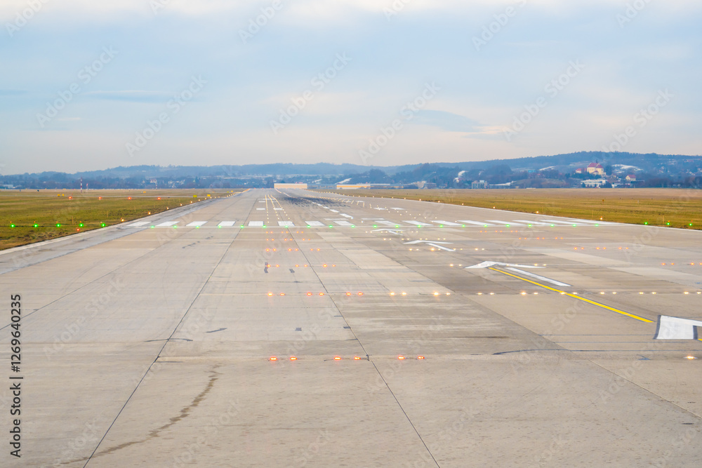 Runway view at an airport showing clear path for takeoff on a cloudy day