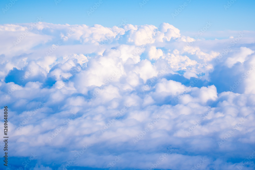 Fluffy clouds emerging under a bright blue sky during a sunny afternoon above mountain ranges Fluffy clouds emerging under a bright blue sky during a sunny afternoon above mountain ranges