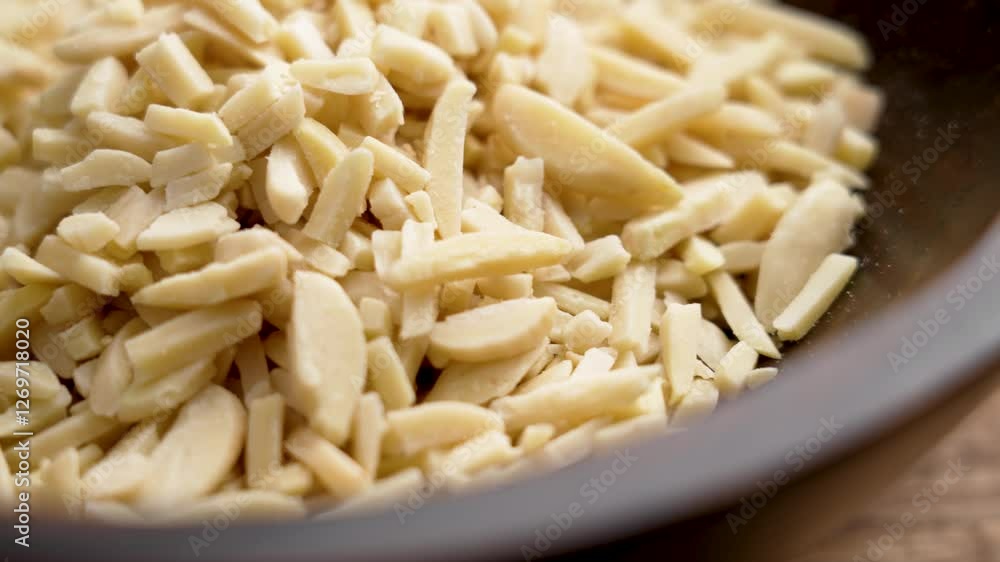 Wooden bowl full of slivered almonds. Chopped nuts used as a baking ingredient. Raw organic topping Wooden bowl full of slivered almonds. Chopped nuts used as a baking ingredient. Raw organic topping