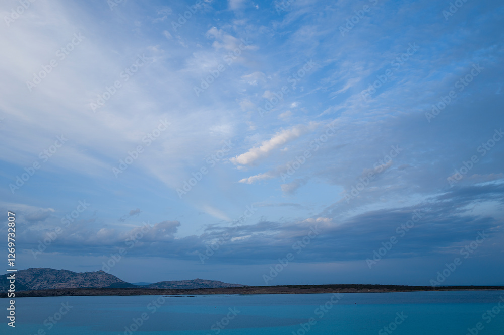 Fototapeta premium Isola Piana seen from La Pelosa beach at sunset in Stintino in Europe, Italy, Sardinia, Stintino, in summer, on a sunny day.
