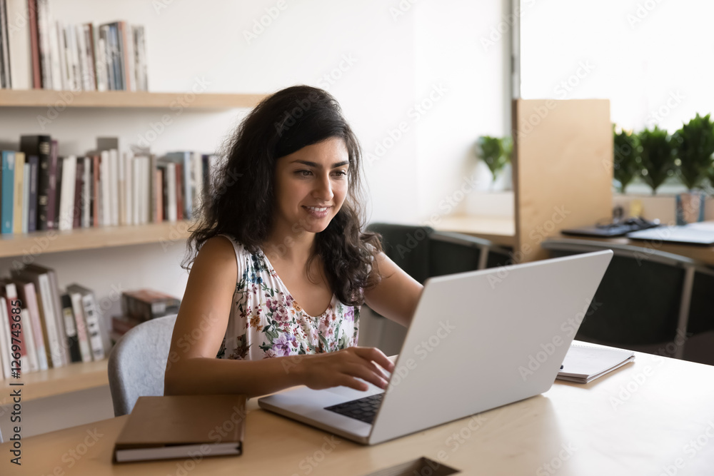 Successful studying. Smiling millennial woman student engaged in online education use notebook in campus library learn with interest enjoy good academic results feel inspired with personal assignment Successful studying. Smiling millennial woman student engaged in online education use notebook in campus library learn with interest enjoy good academic results feel inspired with personal assignment