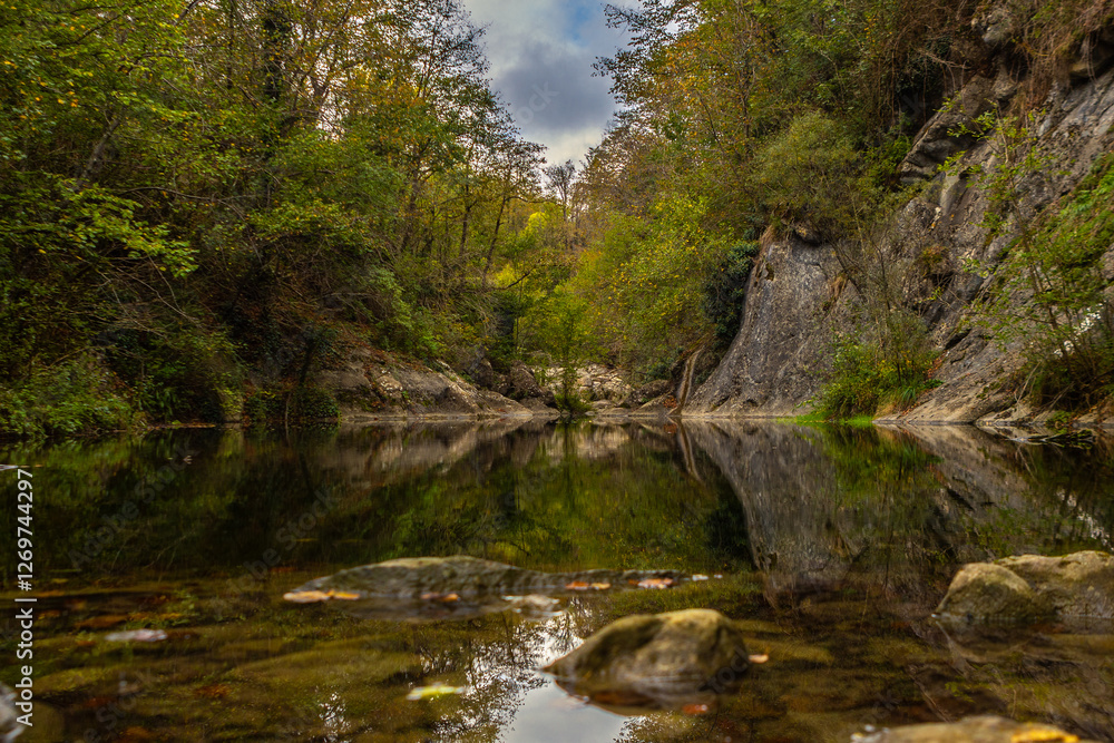 Reflections of rocks, trees and sky in the calm waters of a river Reflections of rocks, trees and sky in the calm waters of a river