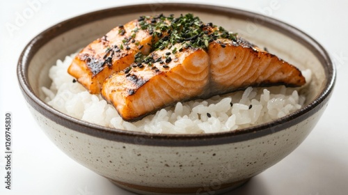 A close-up of a bowl of Japanese rice topped with grilled salmon.