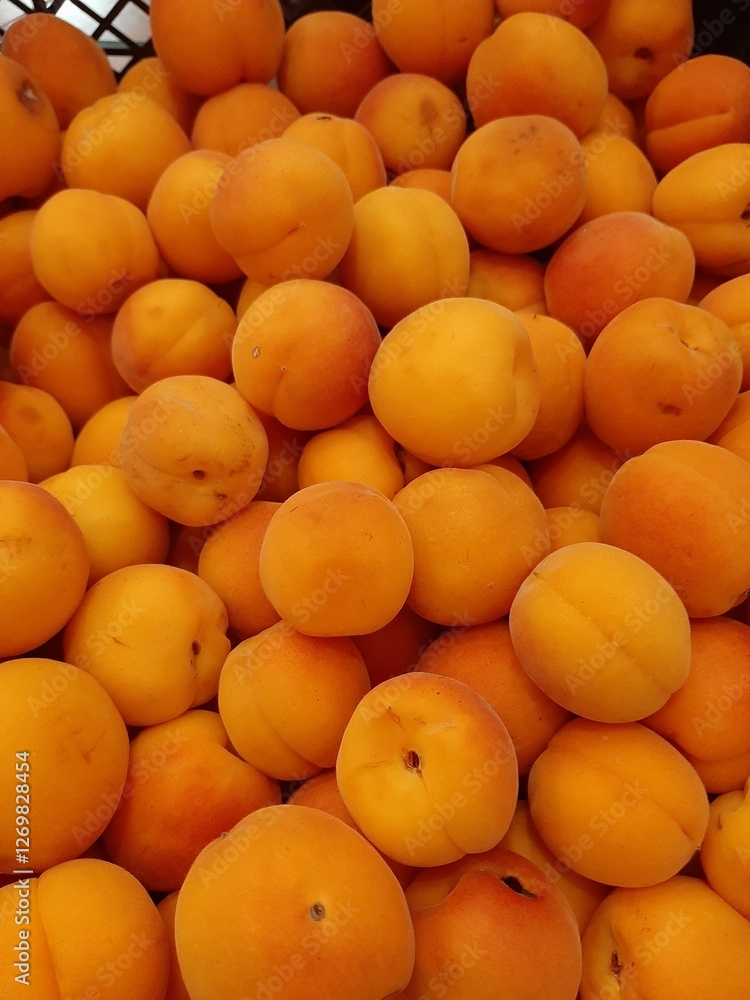 A close-up of fresh, ripe apricots piled together in a crate. The vibrant orange color and smooth texture make them look juicy and delicious, perfect for a healthy snack or dessert. A close-up of fresh, ripe apricots piled together in a crate. The vibrant orange color and smooth texture make them look juicy and delicious, perfect for a healthy snack or dessert.
